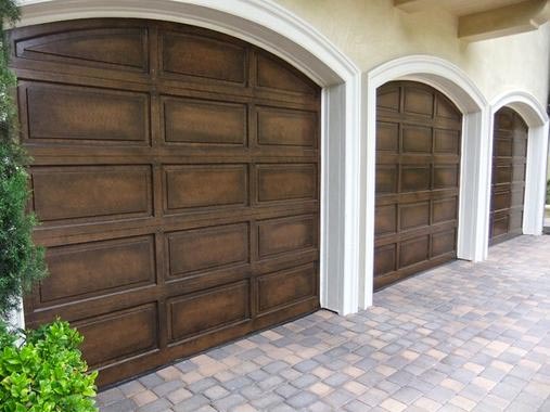 Faux wood finishes painted on metal garage doors to resemble actual hardwood. Looks gorgeous!